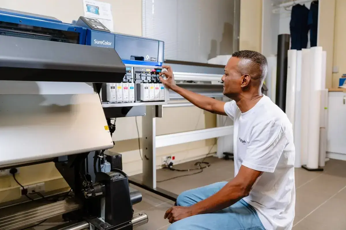 Technician loading ink into an Epson SureColor large-format printer